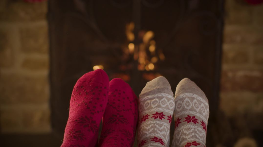 Крупный план ног в рождественских носках на фоне камина