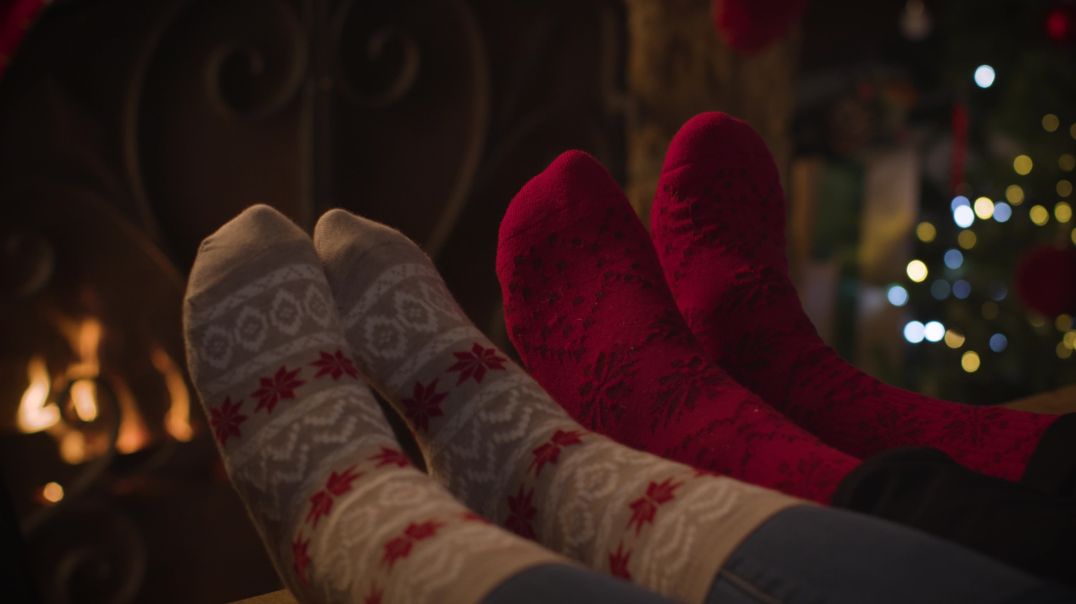 Рождественских видеофон ноги пары в рождественских носках у камина