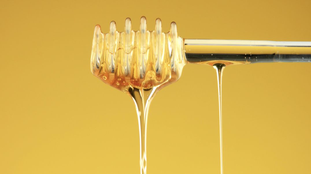 Мед стекает с веретено (ложки для мёда) на жёлтом фоне